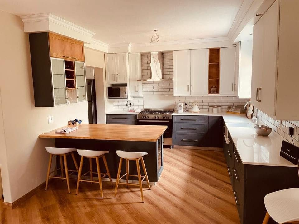 Fitted kitchen with charcoal cabinets, white stone tops and a solid wood breakfast counter