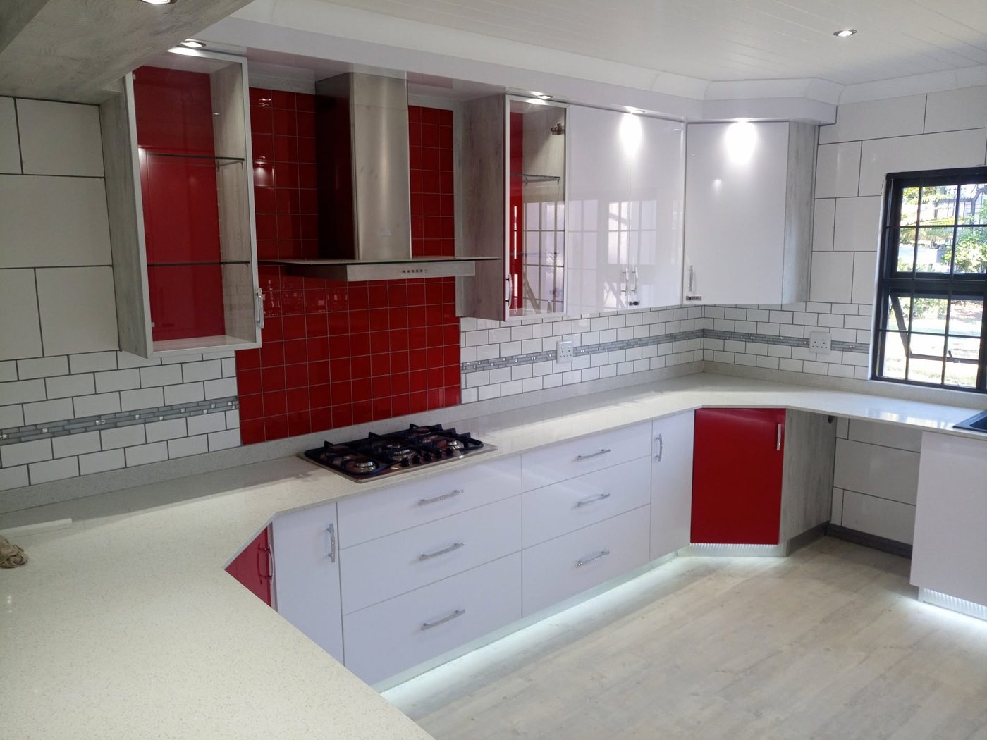 White and red high gloss kitchen with stainless extractor and speckled stone tops
