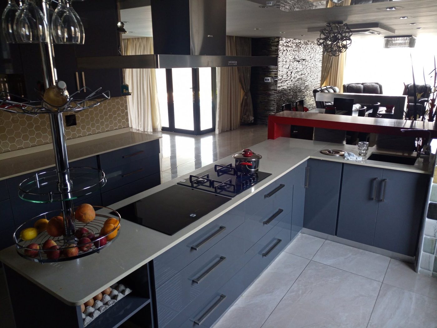 Navy blue gloss kitchen with a long island, gas hob and pale stone tops