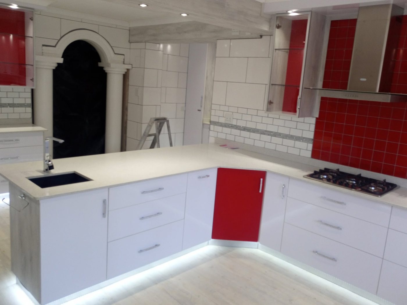 White gloss kitchen with red feature door, subway tiling and under-counter lighting