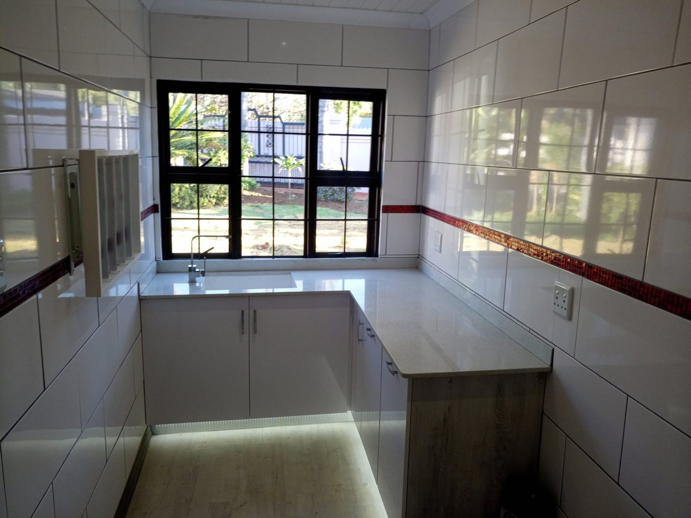 Compact U-shaped white kitchen with stone tops and a window over the sink